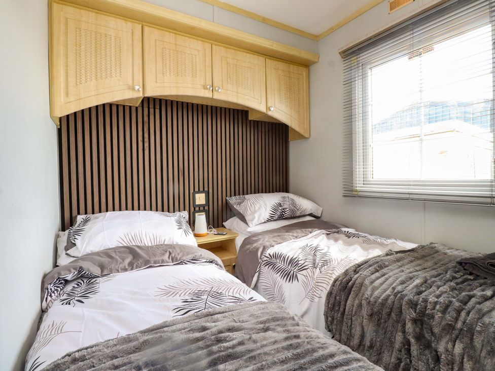 A bedroom with two beds and a window at Caravan at Argraig Llanrhyddlad near Cemaes Bay