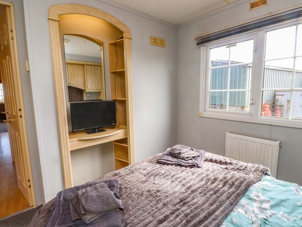 A bedroom with a bed and television at Caravan at Argraig in Llanrhyddlad near Cemaes Bay