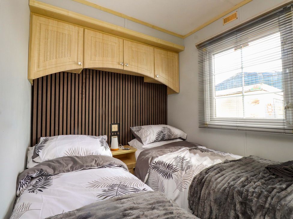 A bedroom with two beds and a window at Caravan at Argraig near Llanrhyddlad near Cemaes Bay