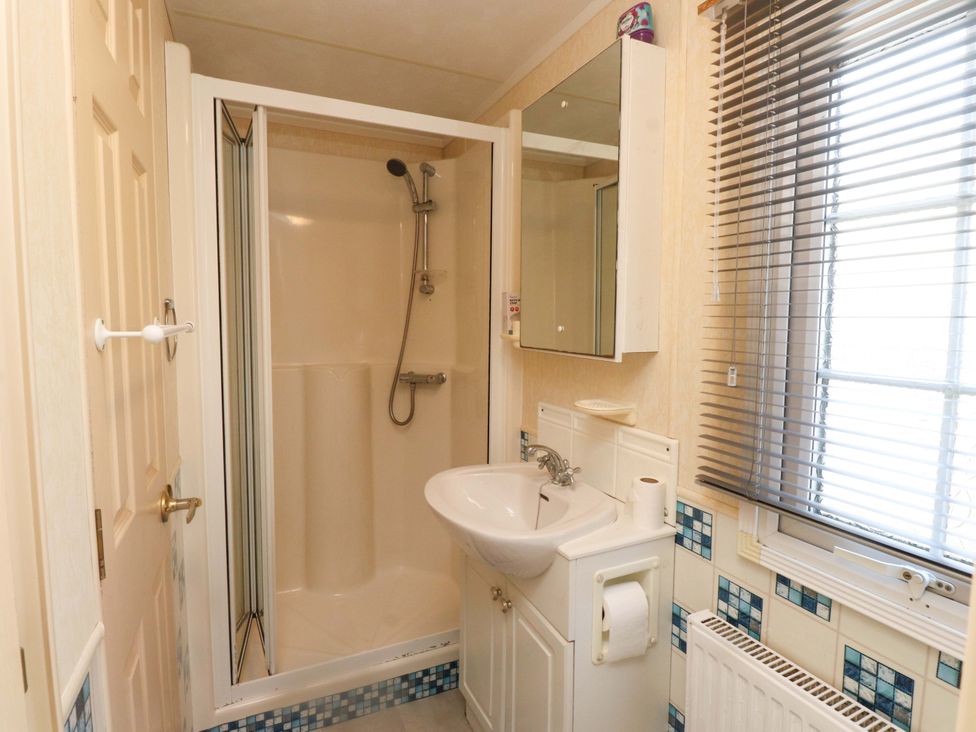 A bathroom with a shower and sink at Caravan at Argraig near Llanrhyddlad near Cemaes Bay