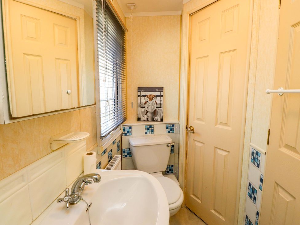 A bathroom with a toilet and washbasin at Caravan at Argraig Llanrhyddlad near Cemaes Bay