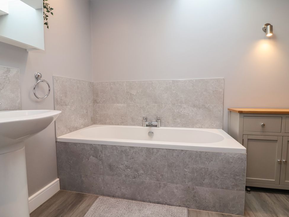 A bathroom with a bathtub, sink and cabinet at Naseby House Morton near Alfreton