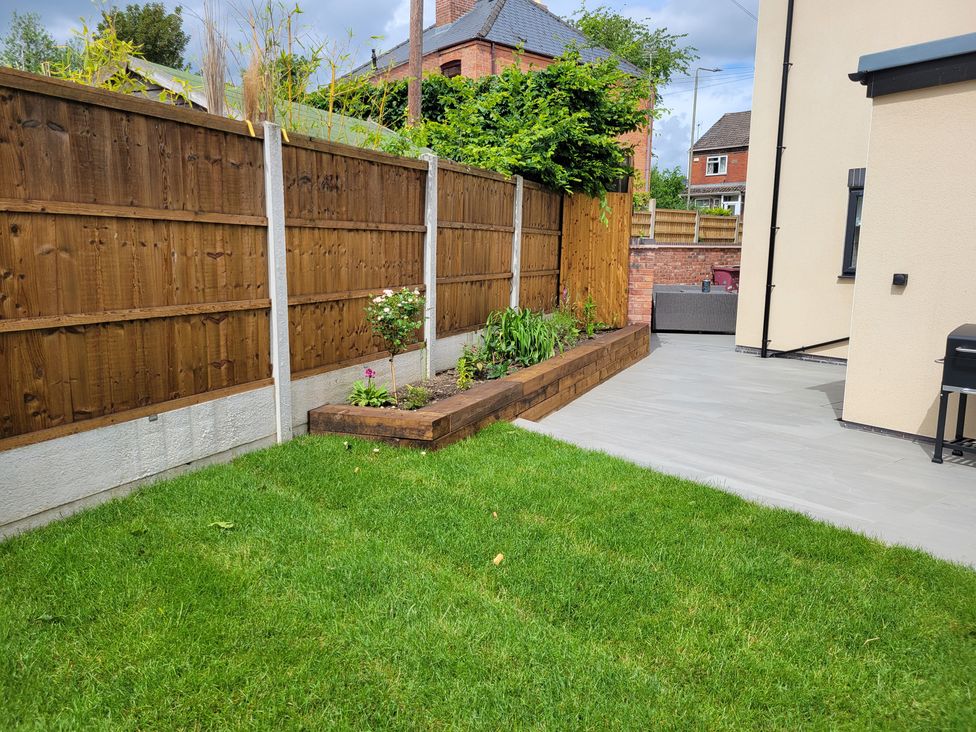 A garden with a fence, grass, and a flower bed at Naseby House Morton near Alfreton