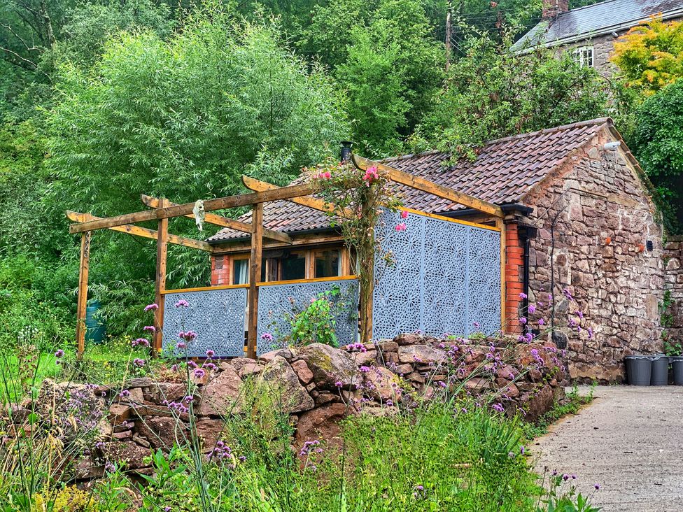 A house with a wooden pergola and stone wall at Ferryman's Lodge in Brockweir