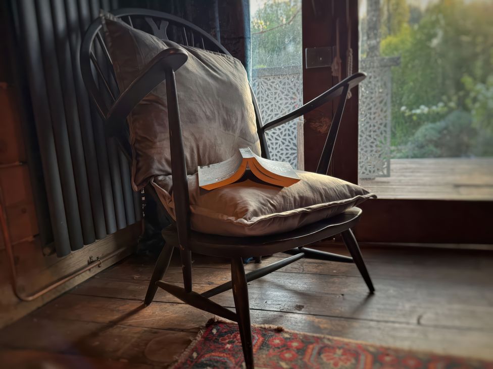 A chair with a cushion and a book placed on it at Ferryman's Lodge in Brockweir