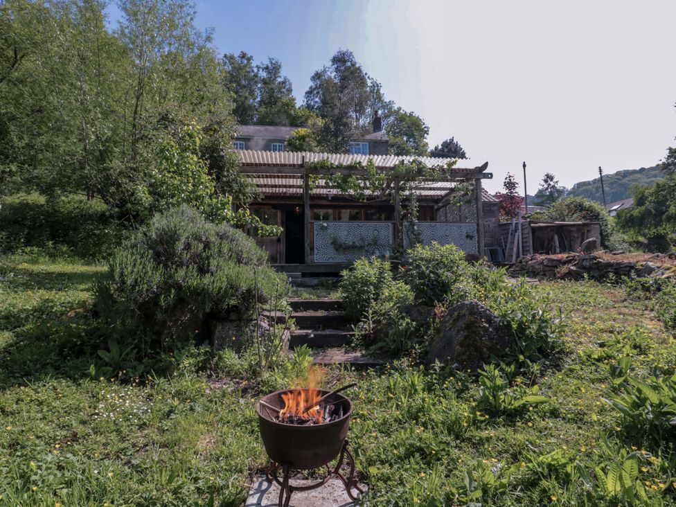 An outdoor area with a fire pit and house view at Ferryman's Lodge in Brockweir