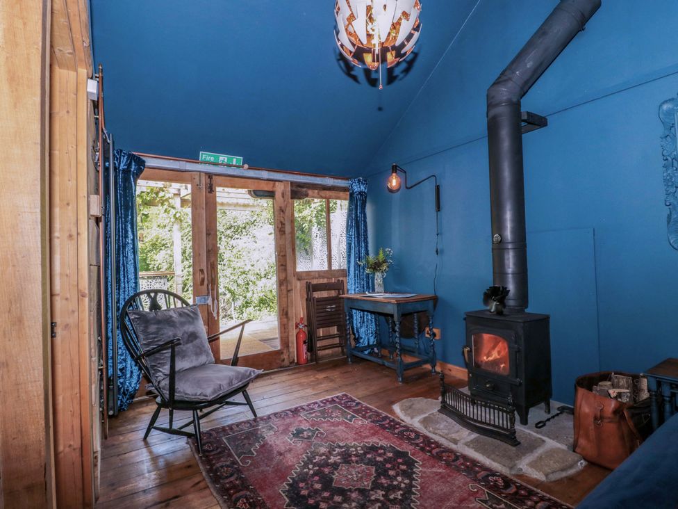 A living room with a stove and chair at Ferryman's Lodge in Brockweir