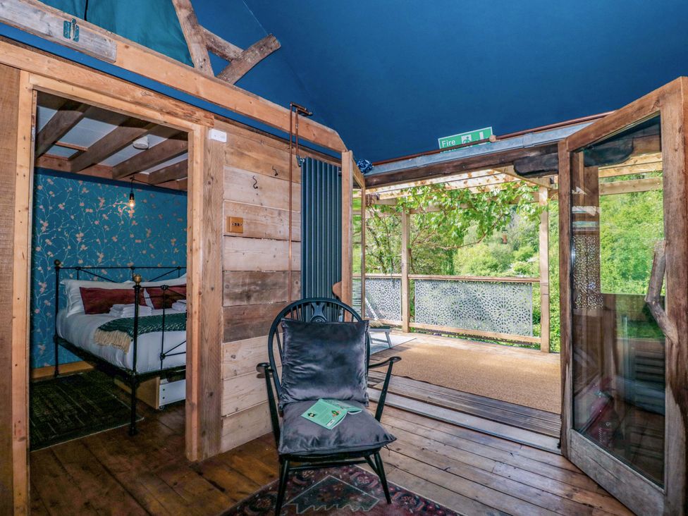 A bedroom with a bed and chair at Ferryman's Lodge in Brockweir