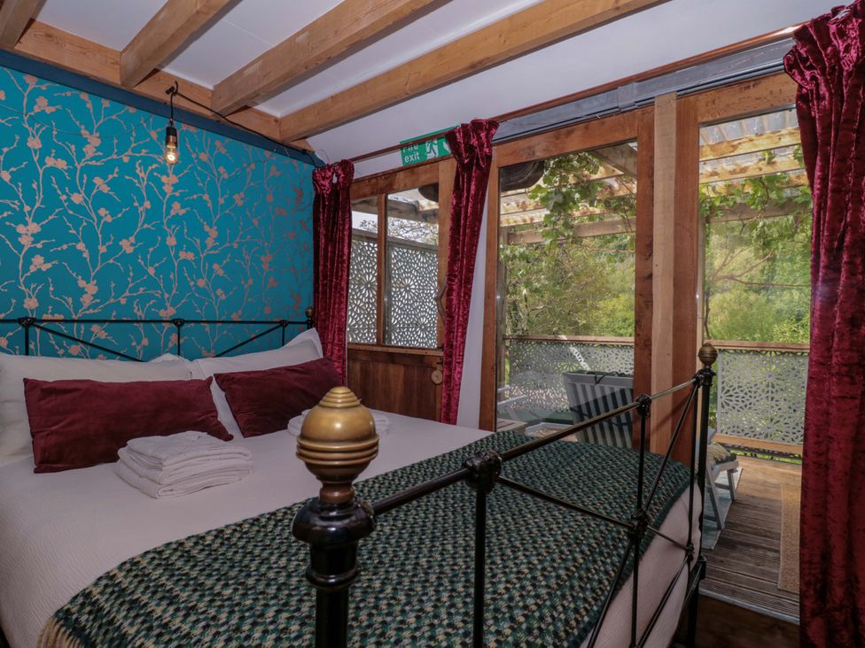 A bedroom with a bed and wooden features at Ferryman's Lodge, Brockweir