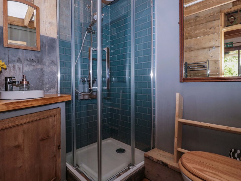 A bathroom with a shower and sink at Ferryman's Lodge in Brockweir
