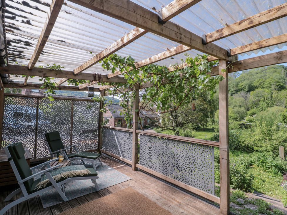A patio area with chairs and a table at Ferryman's Lodge in Brockweir