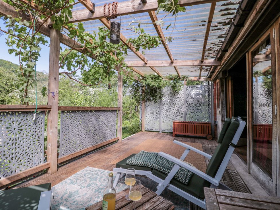 An outdoor deck with chairs and a table at Ferryman's Lodge in Brockweir