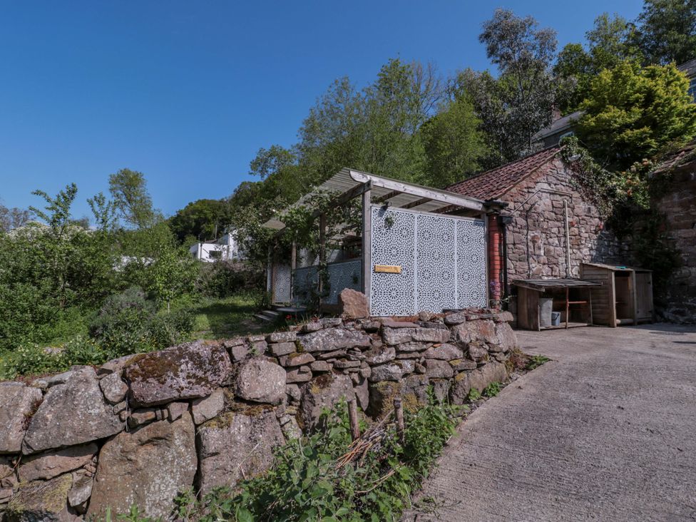 A garden with a stone wall and seating area at Ferryman's Lodge in Brockweir
