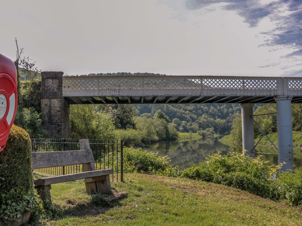 A river with a bridge and a bench nearby at Ferryman's Lodge in Brockweir
