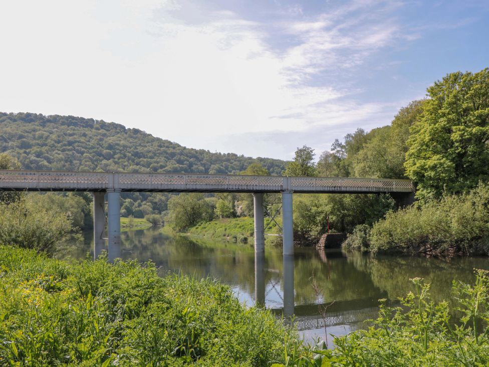 A bridge over a river surrounded by trees and hills at Ferryman's Lodge in Brockweir
