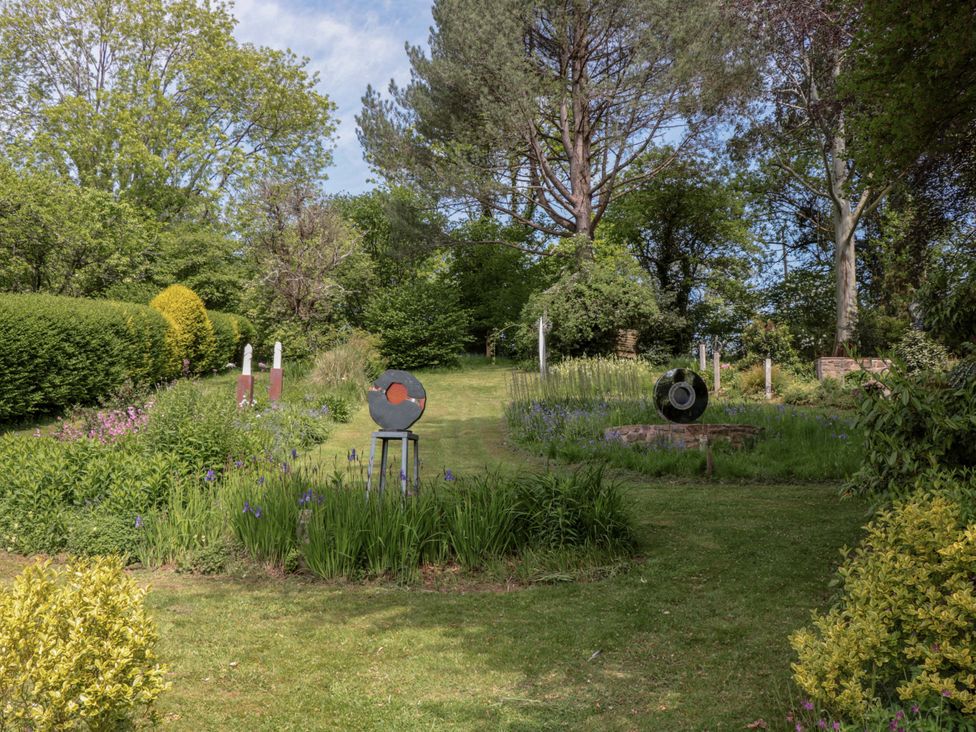 A garden featuring sculptures and various plants at Ferryman's Lodge in Brockweir