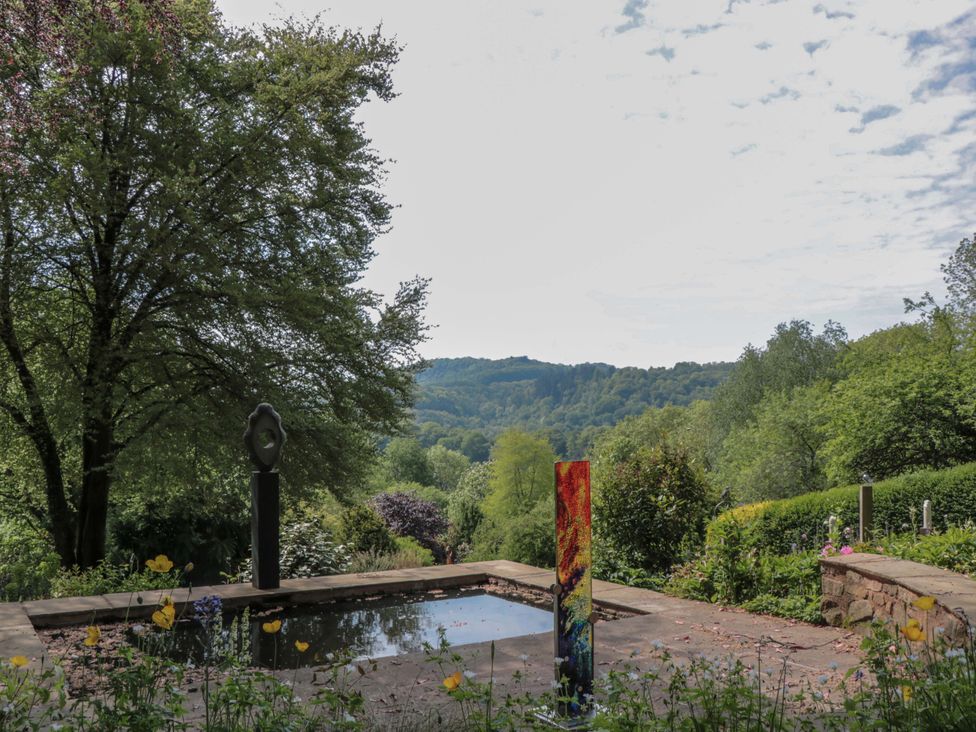 A garden with a water feature and sculpture at Ferryman's Lodge in Brockweir