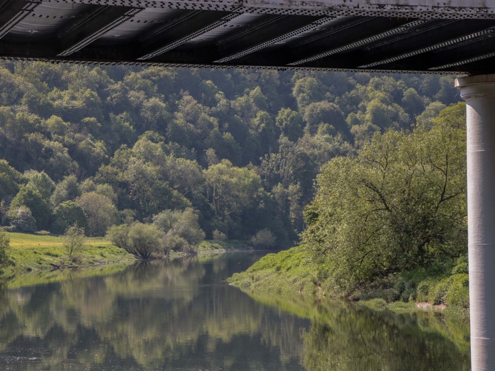 A river with trees and mountains under a bridge at Ferryman's Lodge in Brockweir