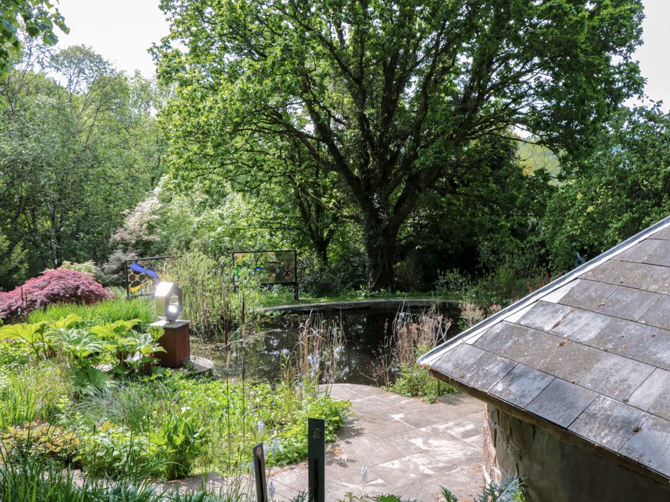A garden with a pond and a tree at Ferryman's Lodge in Brockweir