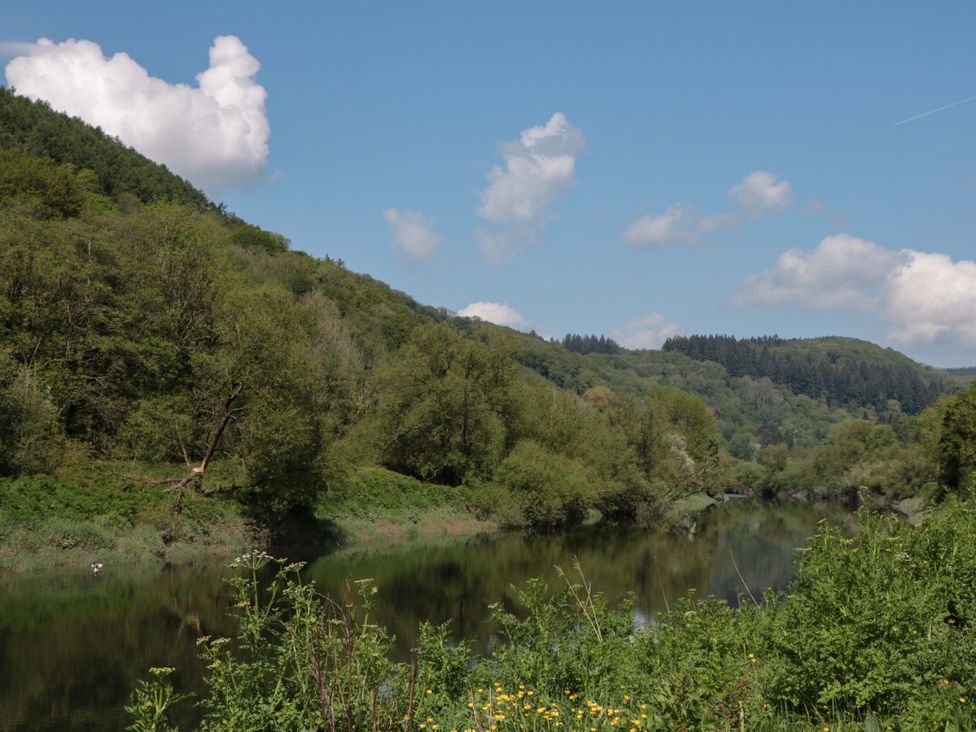 A river surrounded by trees and mountains at Ferryman's Lodge in Brockweir