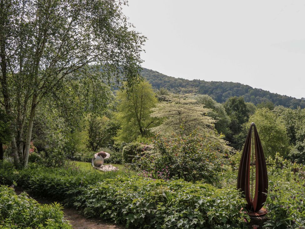 A garden with trees and a sculpture at Ferryman's Lodge in Brockweir