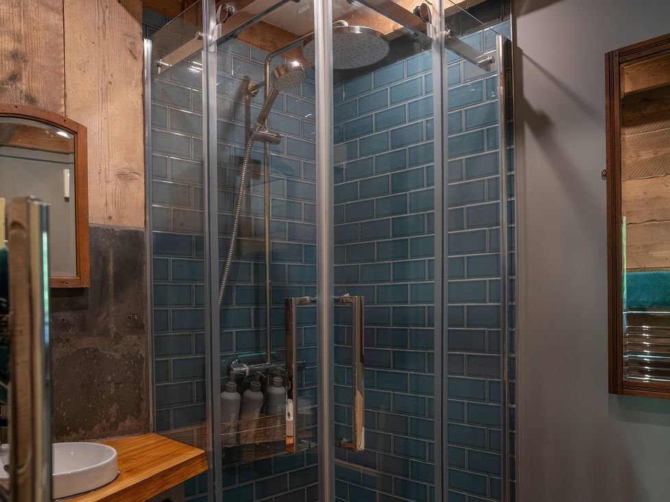 A shower with glass enclosure and tiled walls at Ferryman's Lodge in Brockweir