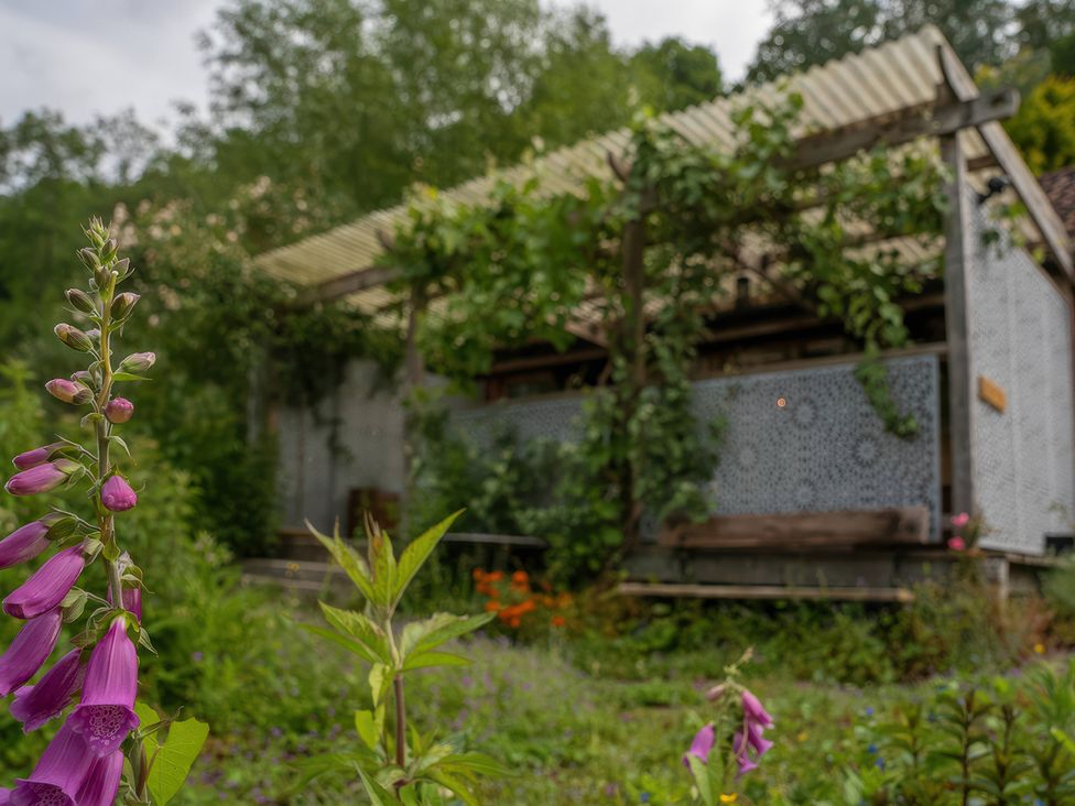 A garden with flowers and an outdoor structure at Ferryman's Lodge in Brockweir