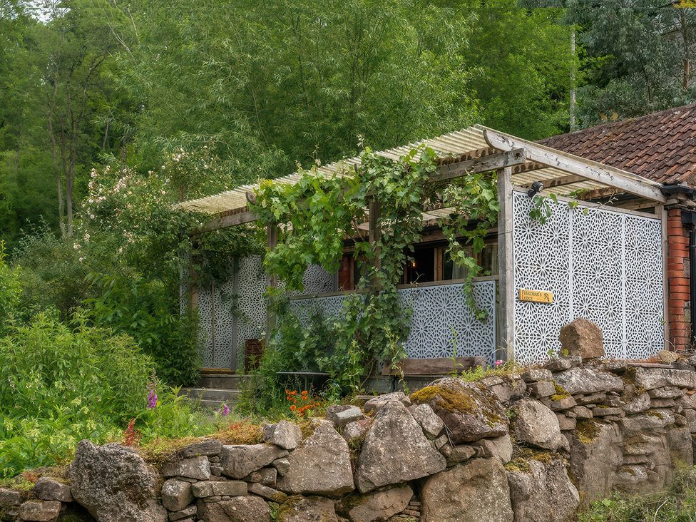 An outdoor area with a wooden structure and decorative wall panel at Ferryman's Lodge in Brockweir