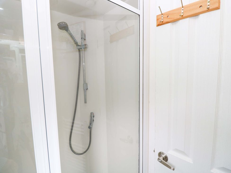 A shower with glass door and hooks at Caravan in Cowes