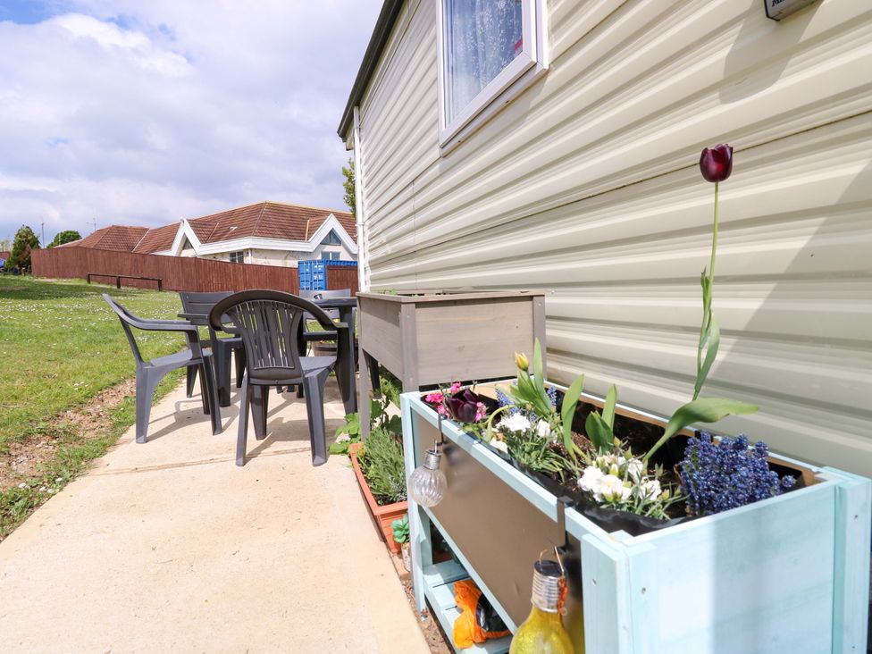 A patio area with a table and chairs beside a flower box at Caravan in Cowes