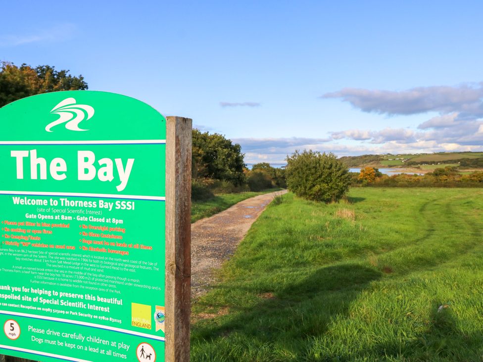 A sign at Thoress Bay SSSI with a path and green fields in Cowes