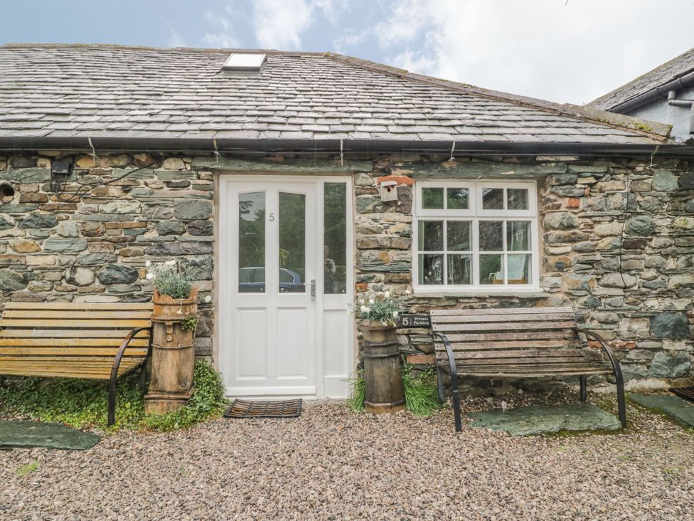 A garden area with a stone wall and bench at Mews Cottage 5 Keswick