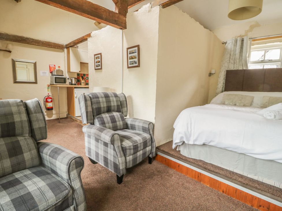 A bedroom with two chairs and kitchenette at Mews Cottage 5 Keswick