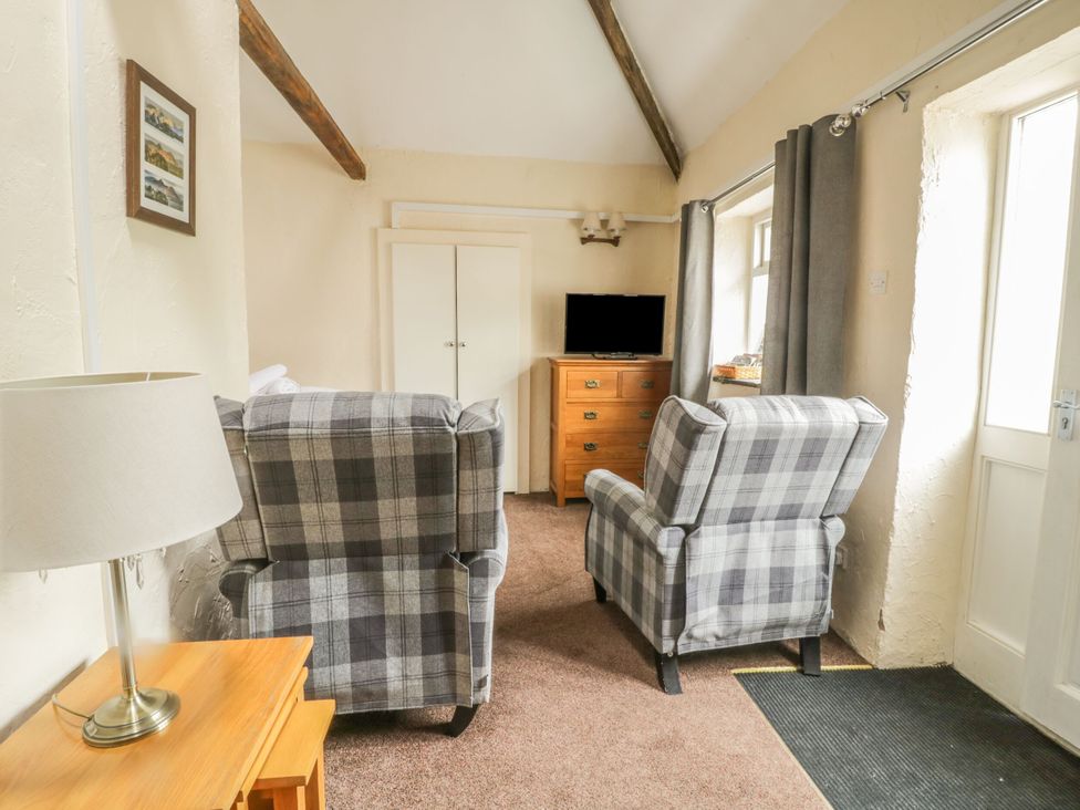 A living room with armchairs and a television at Mews Cottage 5 in Keswick