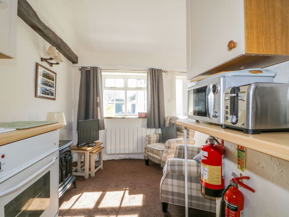 A living room with a television and an armchair at Mews Cottage 6 in Keswick