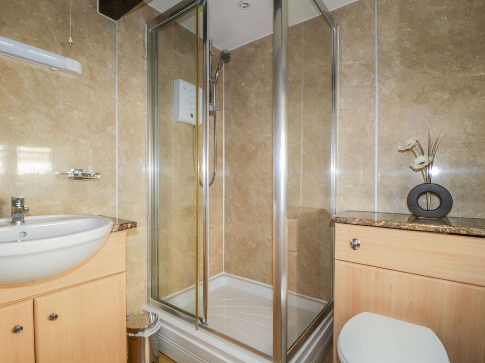 A bathroom with a shower, sink, and toilet at Mews Cottage 6 in Keswick
