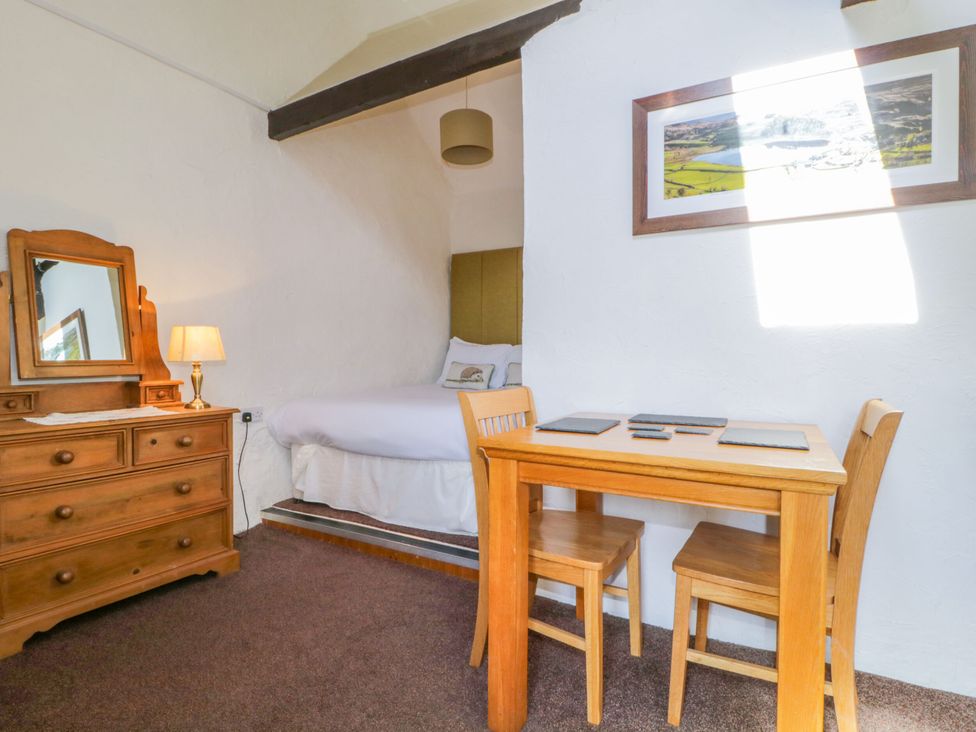 A bedroom with a bed and a table in Mews Cottage 6 Keswick