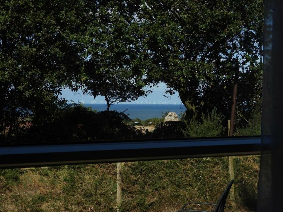 A view of the ocean with wind turbines from a window at Lifes A Beach in Holt