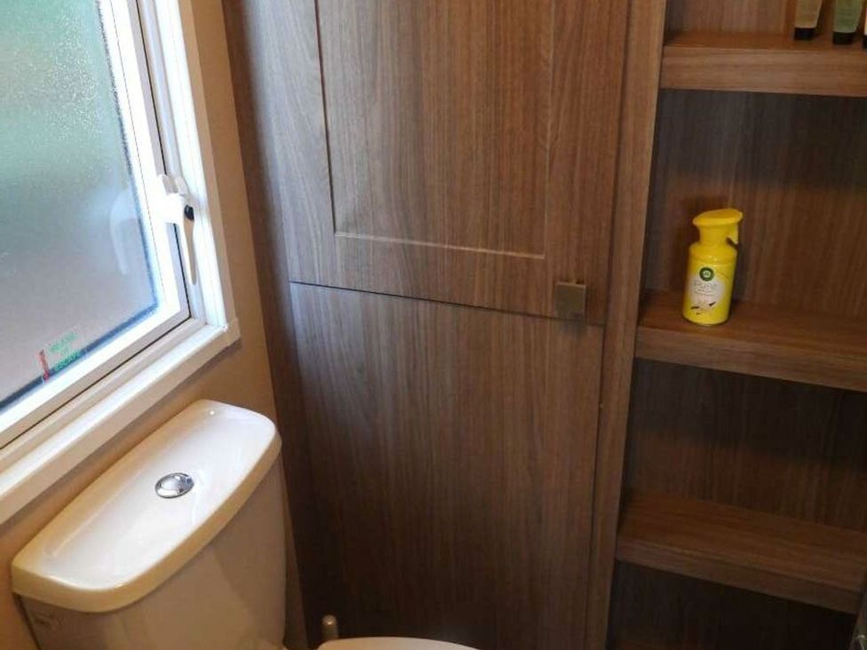 A bathroom with a toilet and wooden shelving at Lifes A Beach in Holt