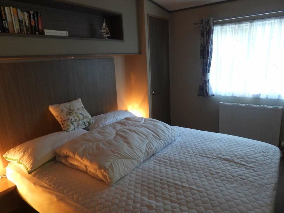 A bedroom with a bed and books on a shelf at Lifes A Beach in Holt