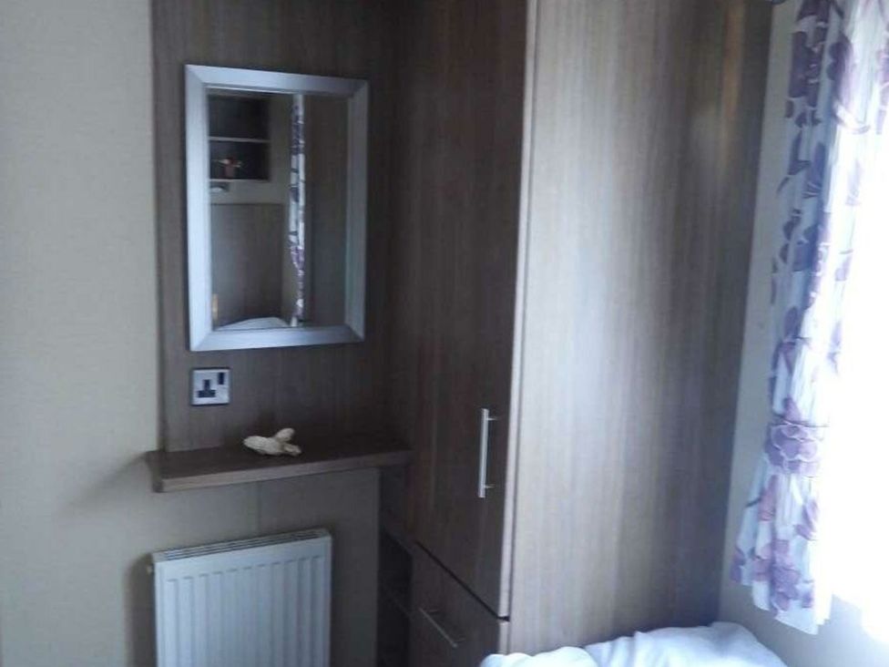 A bedroom with a wardrobe and mirror at Lifes A Beach in Holt