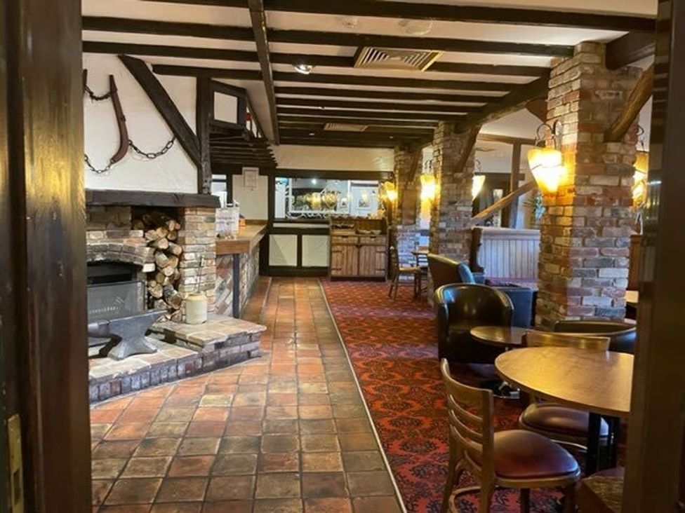 A bar area with a fireplace and tables at Living The Dream in Holt