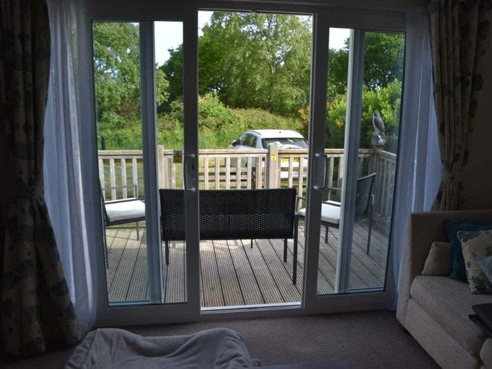 A living room with glass door leading to a deck at Another Day In Paradise in Holt