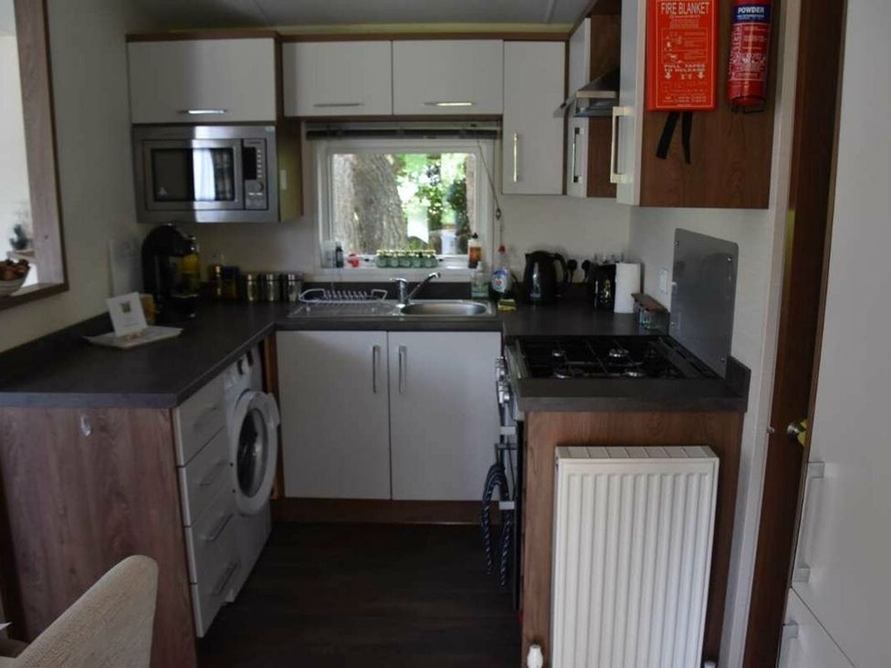 A kitchen with appliances including a microwave and washing machine at Another Day In Paradise in Holt
