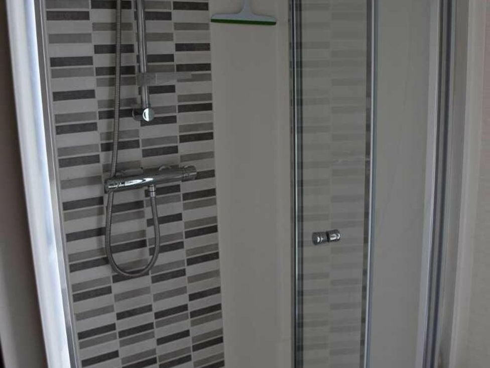A shower with tiles and glass door at Another Day In Paradise in Holt