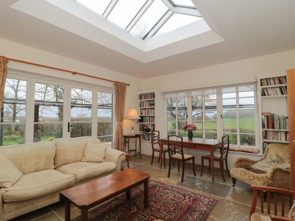A snug room with a sofa, table, and bookshelf at Tuxwell Lodge in Spaxton near Nether Stowey
