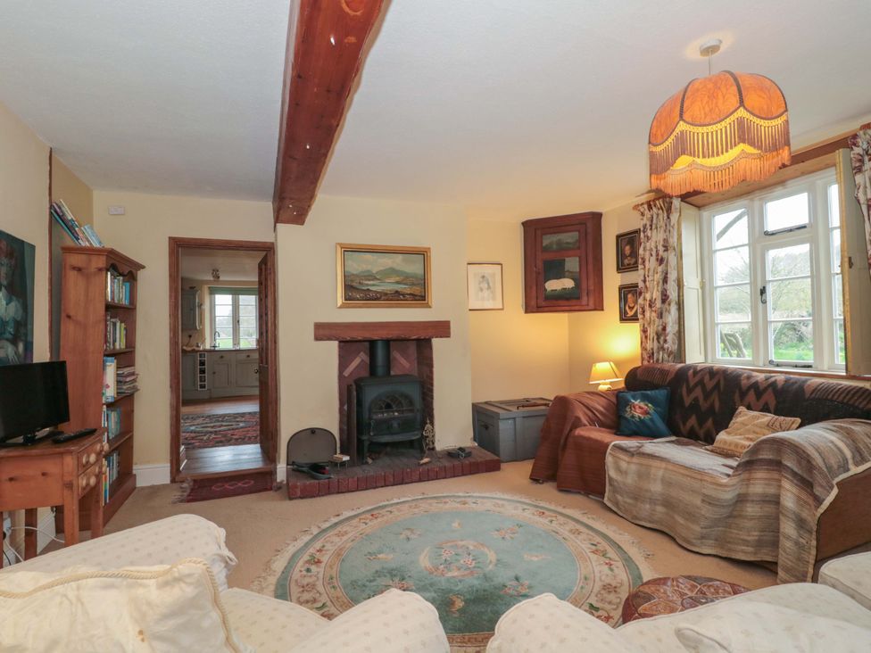 A living room with a fireplace and bookshelves at Tuxwell Lodge in Spaxton near Nether Stowey