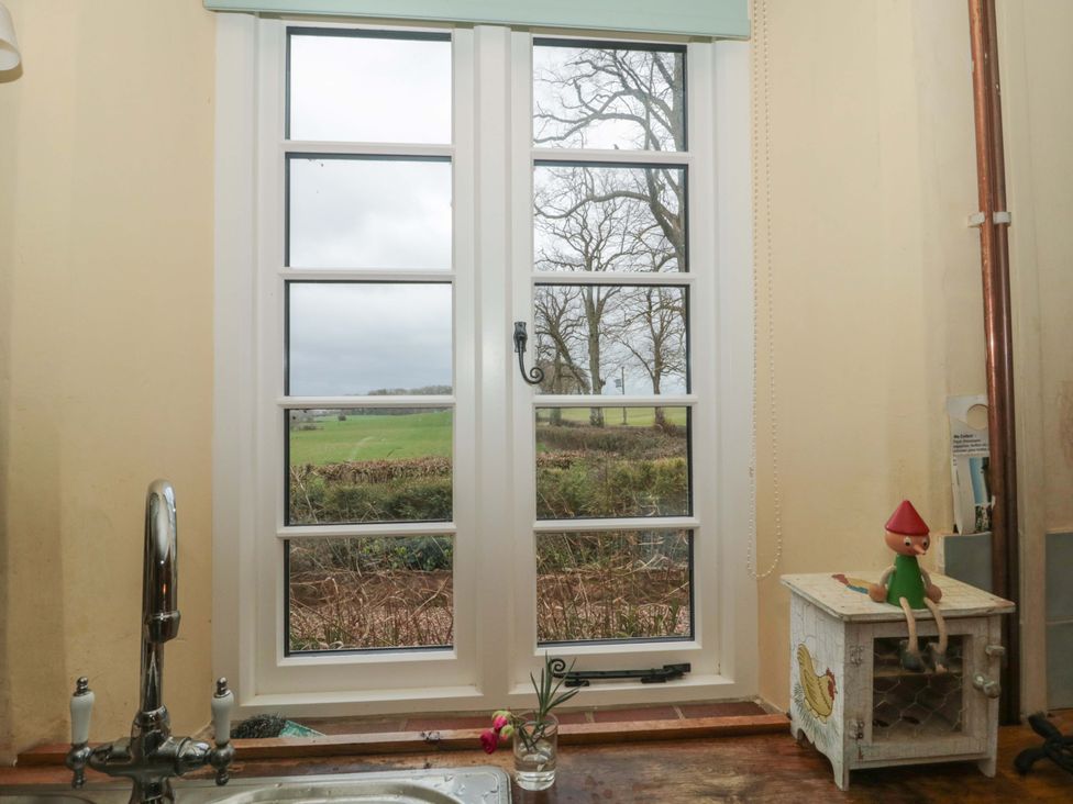 A kitchen window with a view and a small cabinet at Tuxwell Lodge Spaxton near Nether Stowey