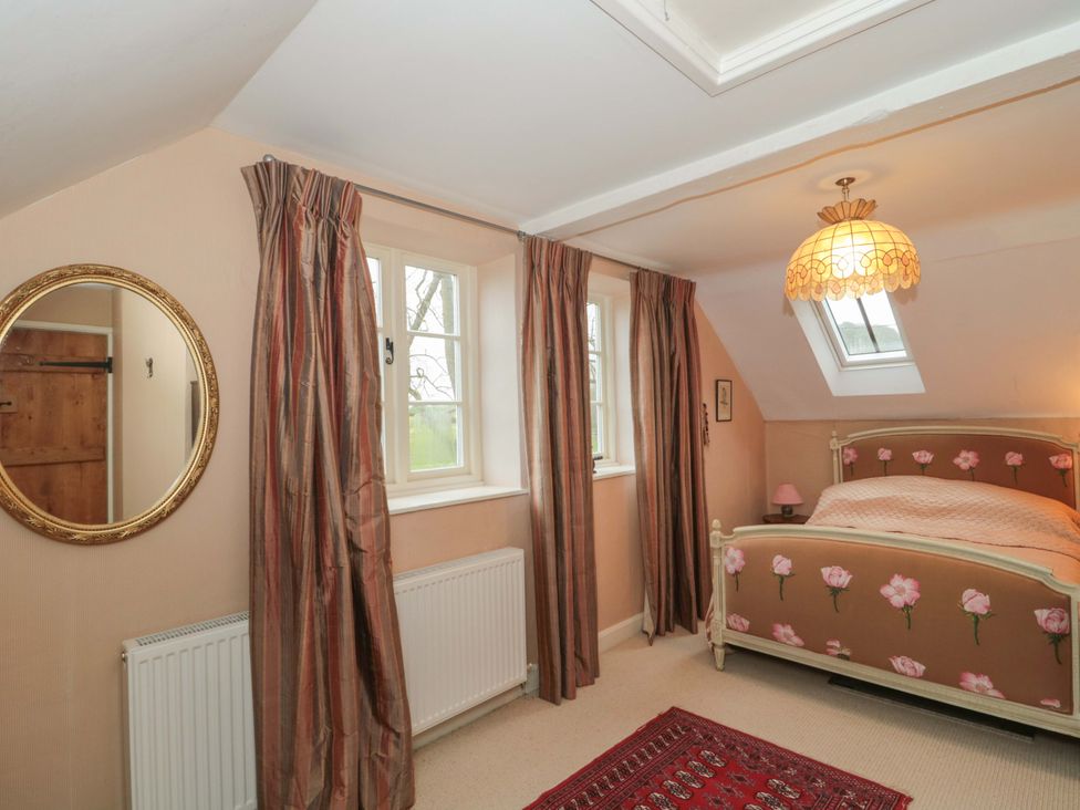 A bedroom with a bed and windows at Tuxwell Lodge in Spaxton near Nether Stowey