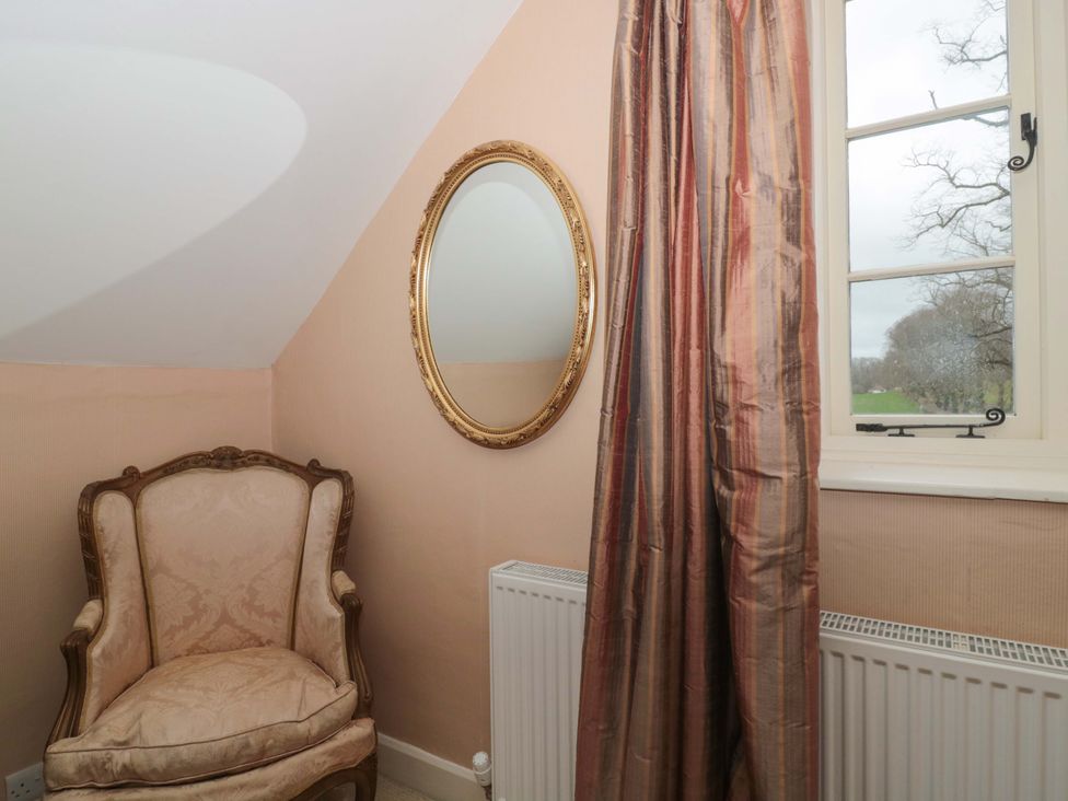 A sitting room with an armchair and a mirror at Tuxwell Lodge in Spaxton near Nether Stowey